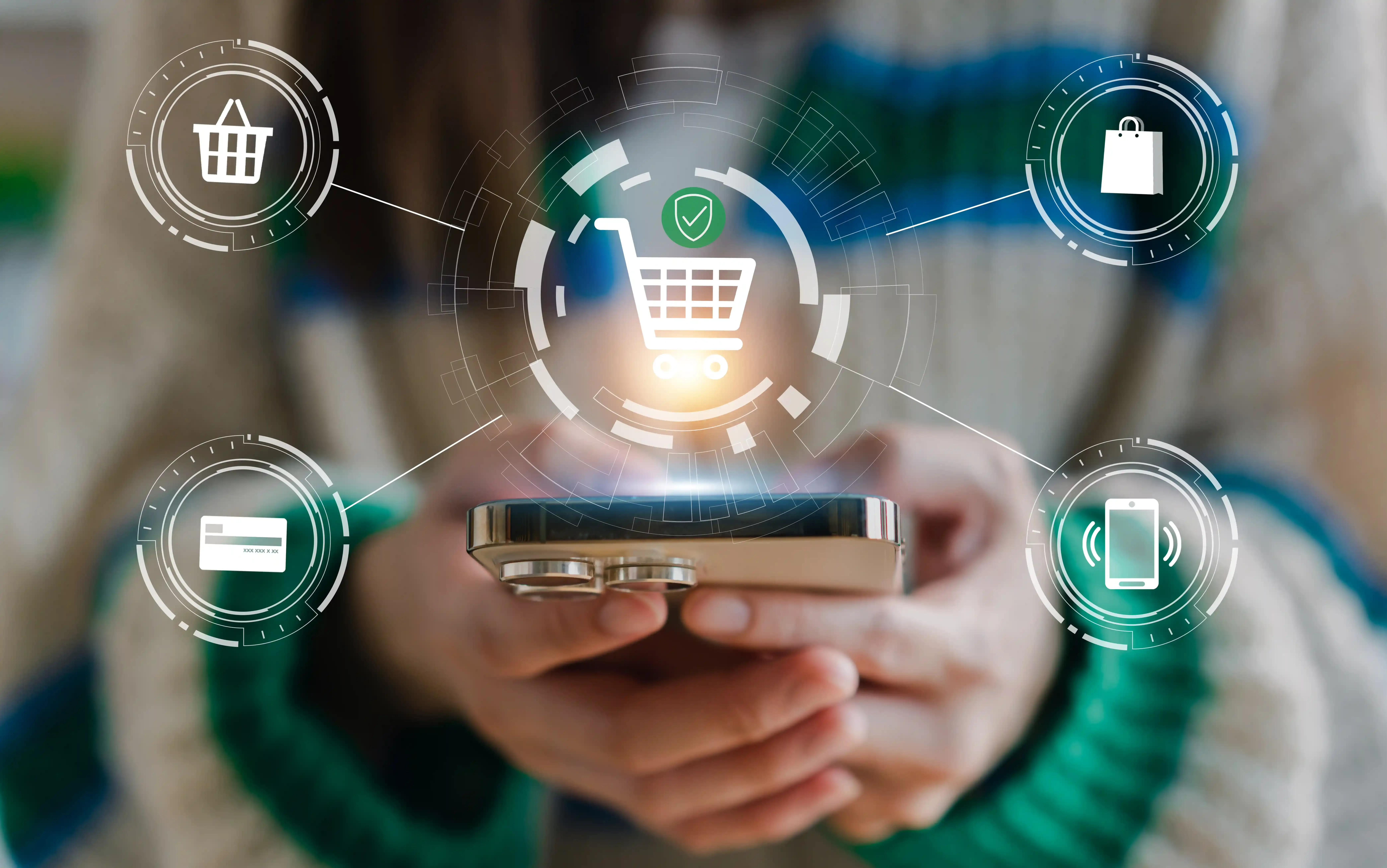 Person holding a smartphone with digital shopping icons overlaid, including a shopping cart, credit card, shopping bag, and mobile payment symbols.