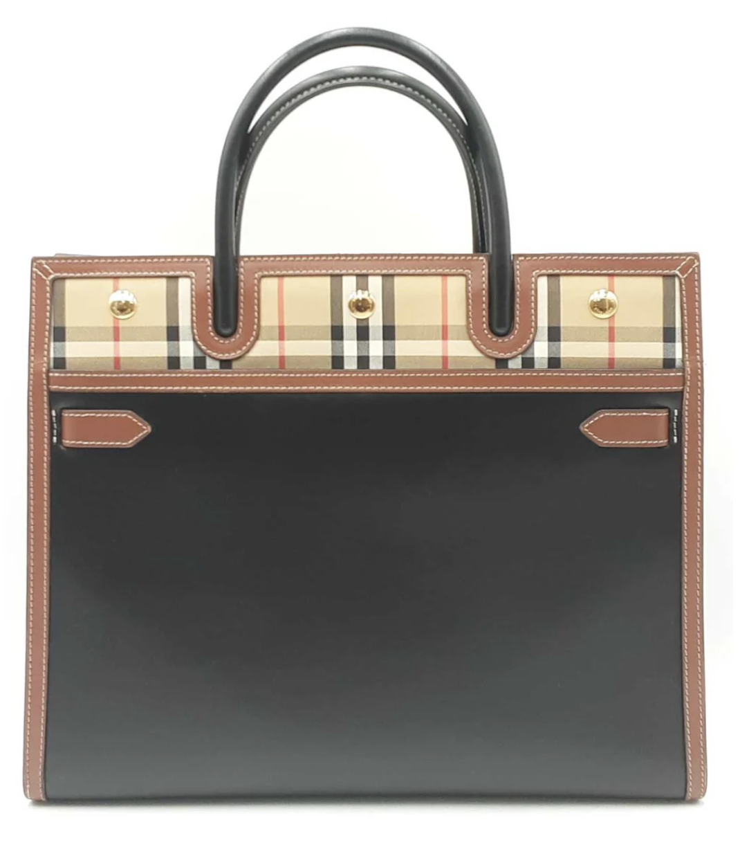 A designer Burberry tote bag featuring a distinctive plaid pattern with brown leather trim and black handles, set against a plain background.