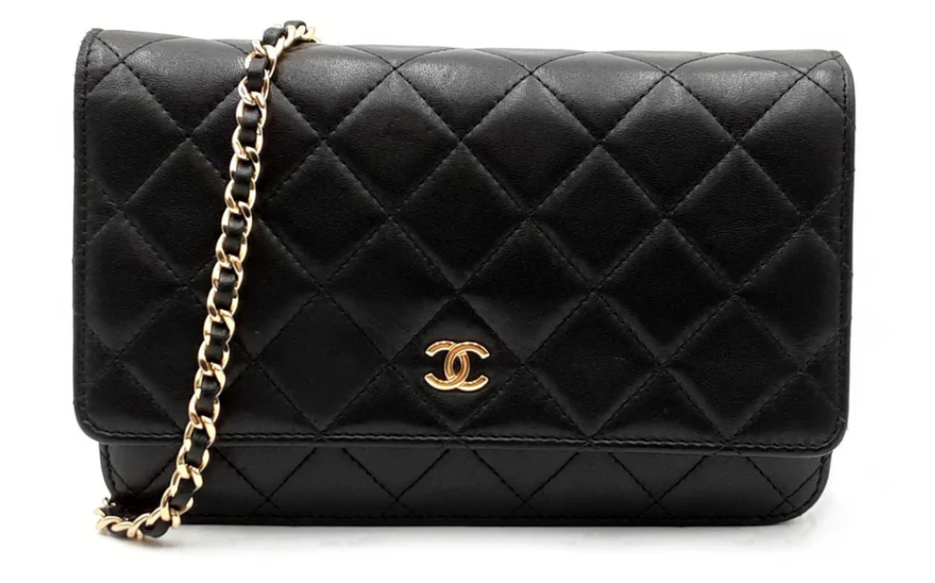 A black quilted Chanel designer handbag with a chain link shoulder strap and a gold logo on the front.