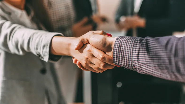 Two people shaking hands, indicating an agreement or deal being made.