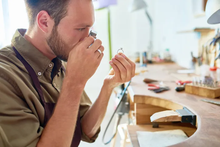 A pawn shop Team Member examining a ring using a magnifying glass, indicating a detailed inspection of the jewelry.