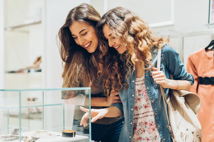 Two women looking at jewelry in a display case, indicating they are considering making a purchase.