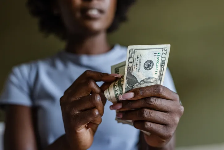 A women in a purple shirt is counting cash.