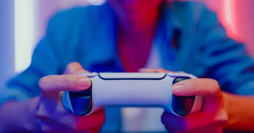 A person holding a video game controller, highlighting the intensity and engagement of the player with colorful neon lighting.